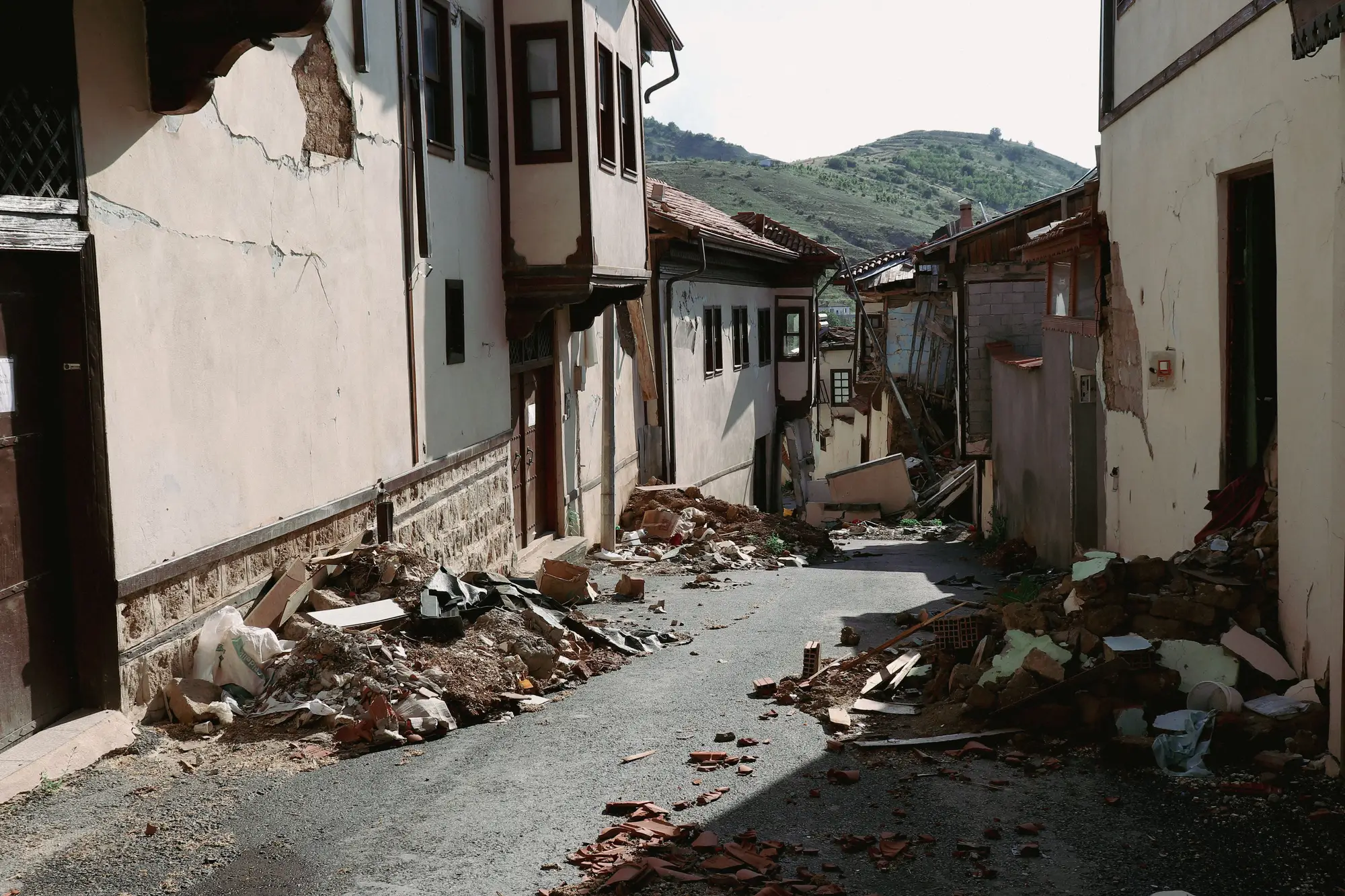 A village street after an earthquake, with fallen masonry and roof tiles along both sides